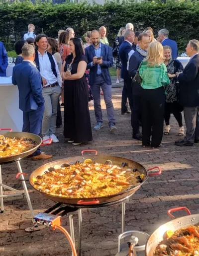 Garden reception with multiple paella pans at an embassy event in Tallinn